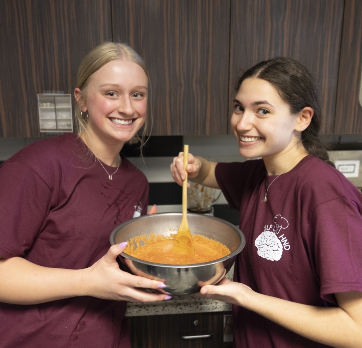 Two students mixing ingredients in a mixing bowl