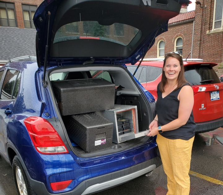 Buffalo State Volunteer Kristen Mruk smiling and standing near her open hatchback packed with food