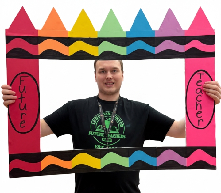 Male student holding a frame that says future teacher