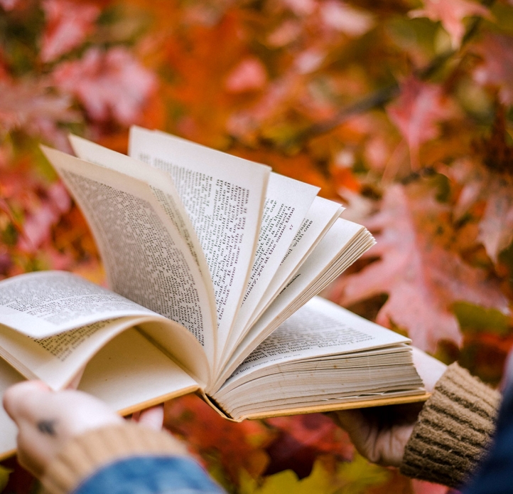 Student fanning a book with leaves in background