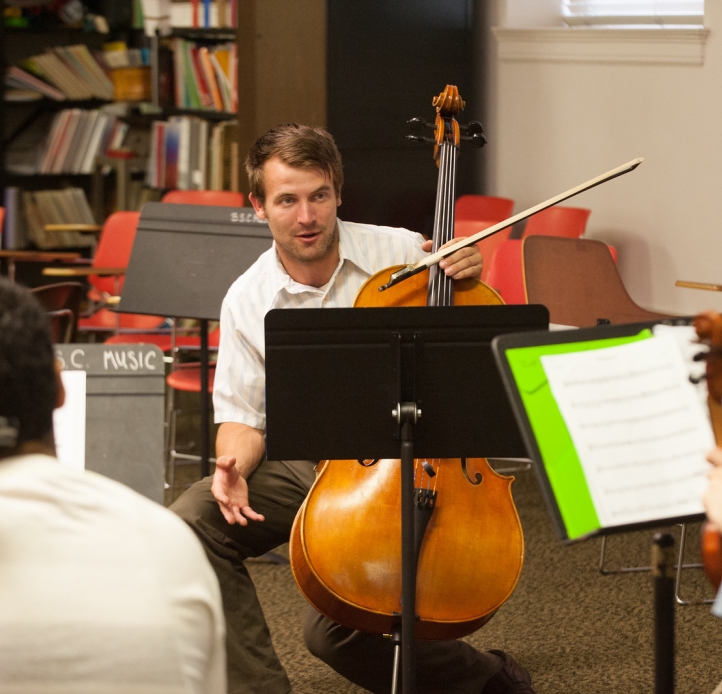 Music teacher with cello instructs students