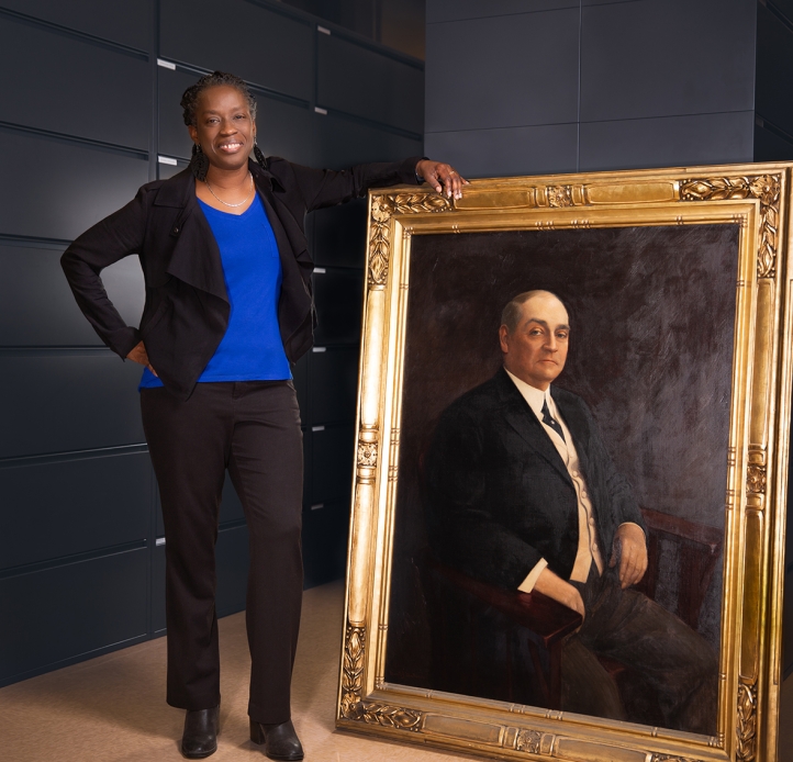 Sheila Rayam stands next to life-size portrait of Edward H. Butler Sr. 