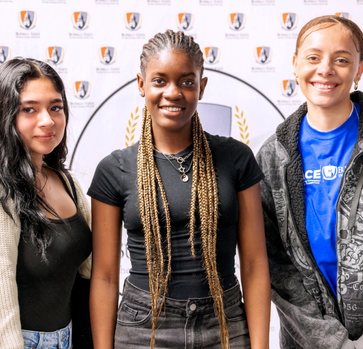 Three students in front of a Buffalo State backdrop