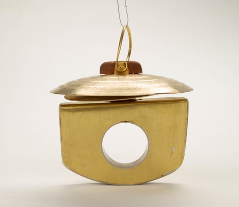 Brass design jewelry item, hole in center, symbol on top