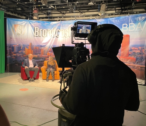 Student behind the camera filming an episode