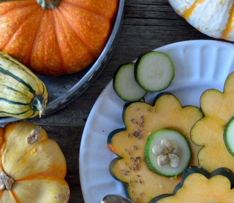 Squash and gourds, some cut in slices to look like flowers and arranged on a plate