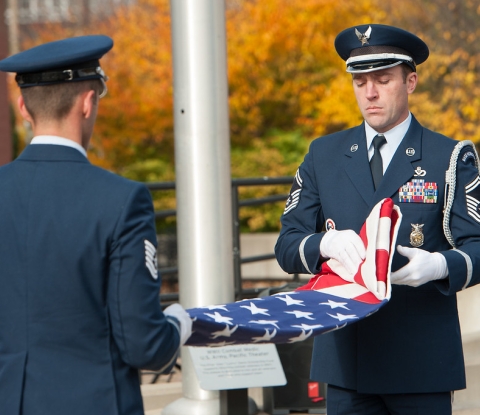 Two service members participating in a flag folding ceremony