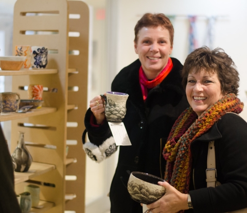 Smiling shoppers holding their wares at the Student Art Sale