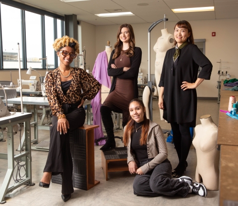 Fashion textile technology students and their faculty adviser pose with sewing machines and dress forms in the fashion laboratory