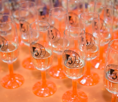 Orange-stemmed champagne glasses with Buffalo State logo