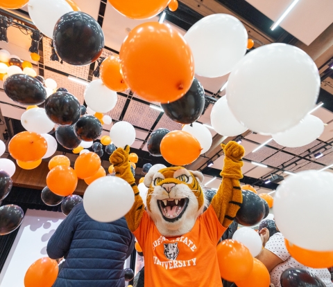 Benji stands in a shower of orange, black, and white balloons