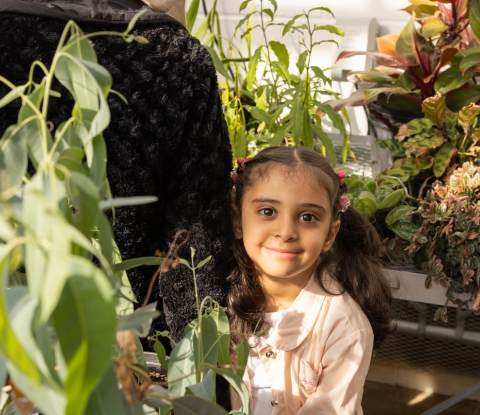 Smiling girl surrounded by plants in the greenhouse