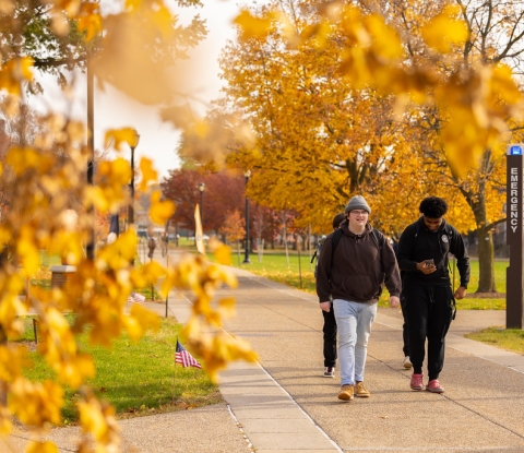 Student walking through campus on a fall day