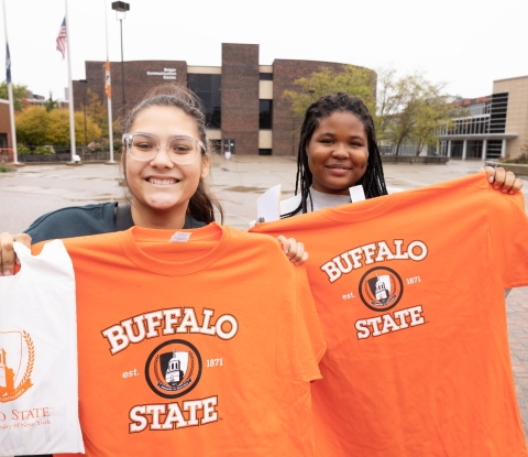 Two prospective students hold Buffalo State t-shirts and smile