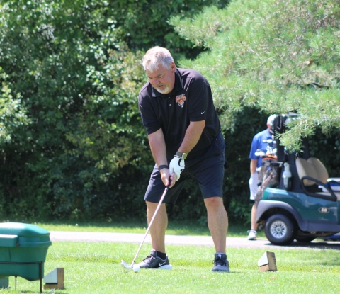 Man wearing a Buffalo State shirt setting up for a golf swing