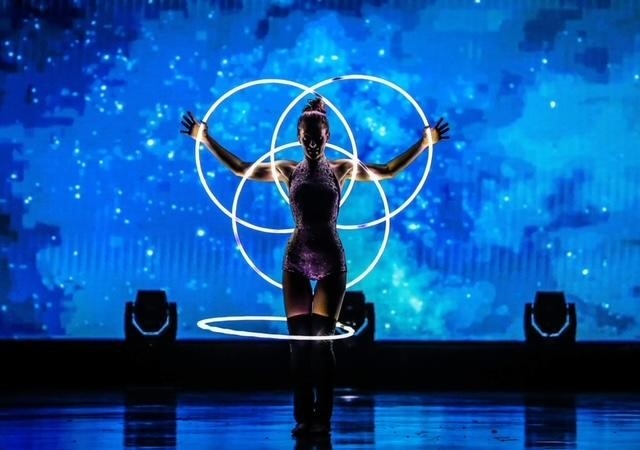 Performer with glowing rings on a blue-lighted stage 