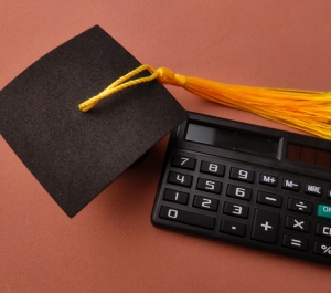 Graduation cap with tassel next to calculator
