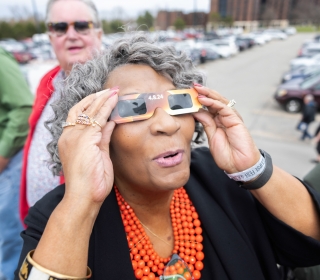 Woman with eclipse glasses looking up