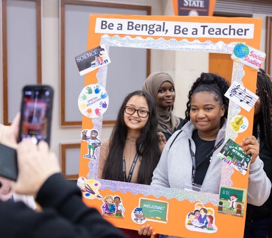 Two prospective students pose with a sign that says Be a Bengal, Be a Teacher