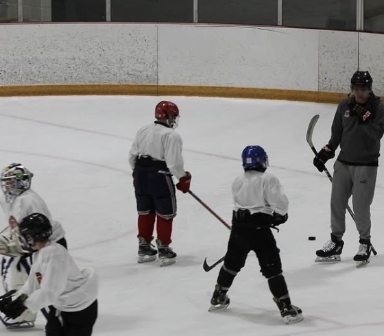 Children and college students in hockey gear on an ice rink