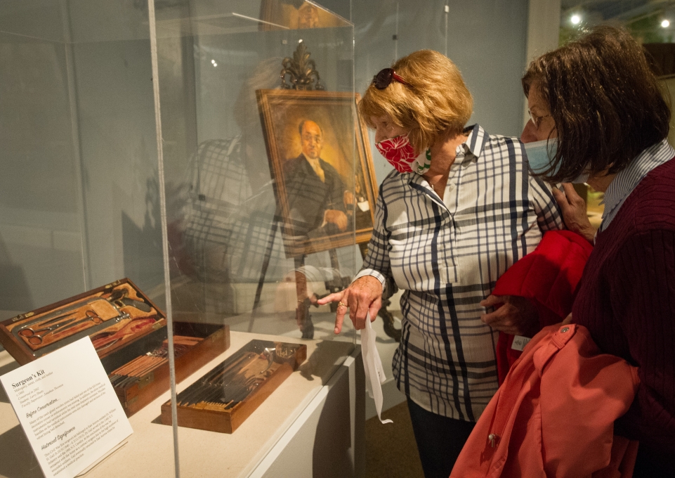 Two women examine the museum display case containing the Civil War surgeon's kit