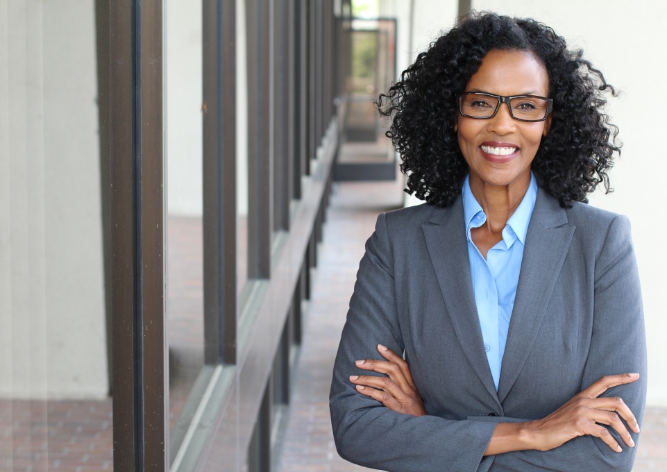 Smiling business woman stands with arms folded
