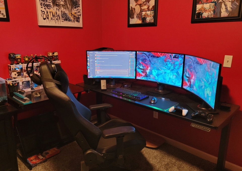 Gaming station with three screens on a desk with chair