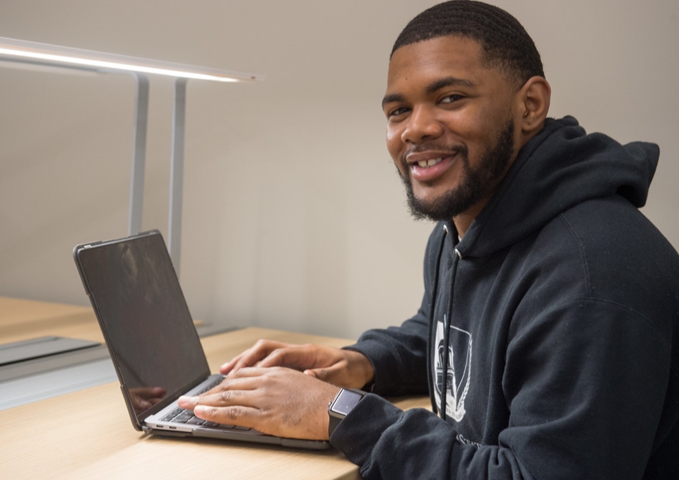 Smiling male student working on a laptop