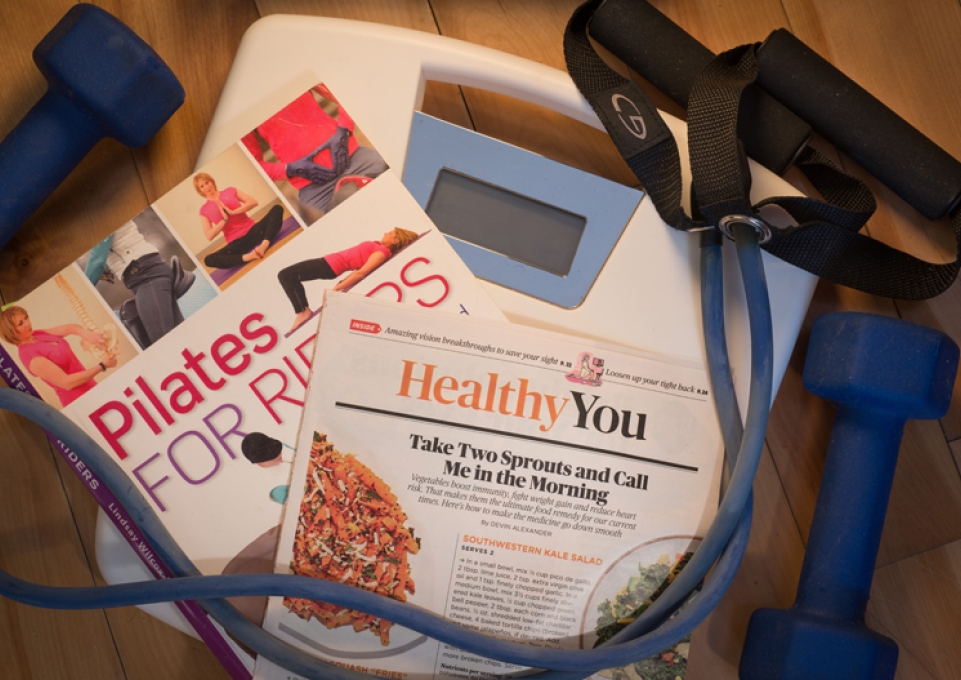 Health and fitness literature, a scale, hand weights, and exercise band arranged on the floor