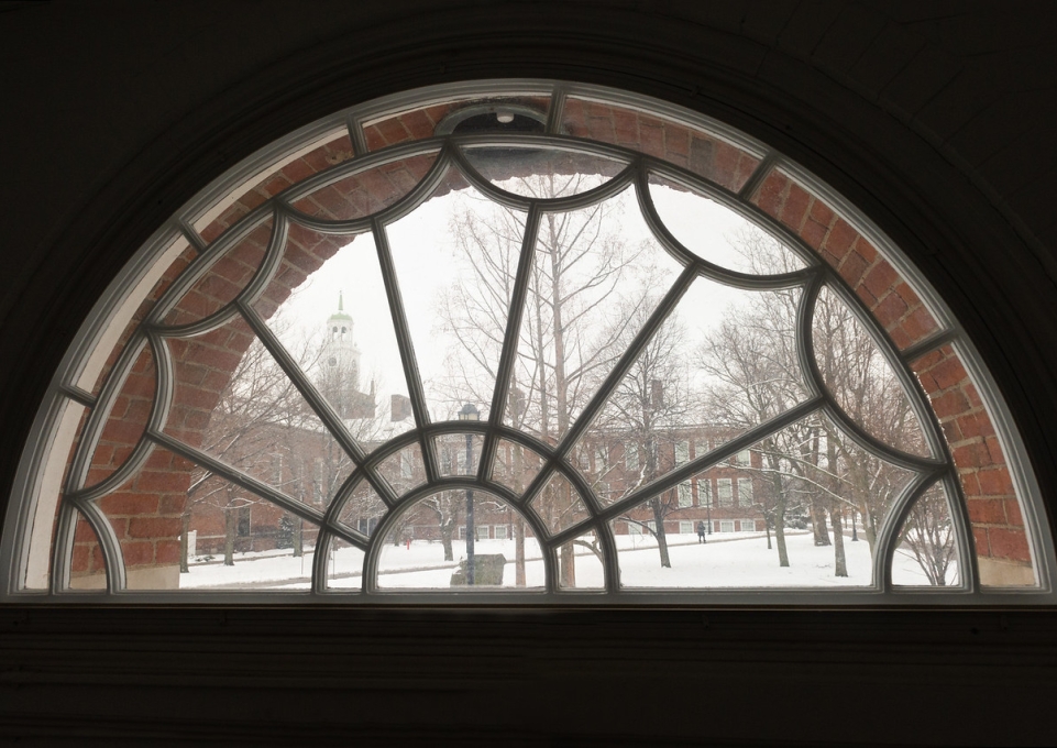 Close up of arched window in Ketchum Hall looing out on snow-covered campus