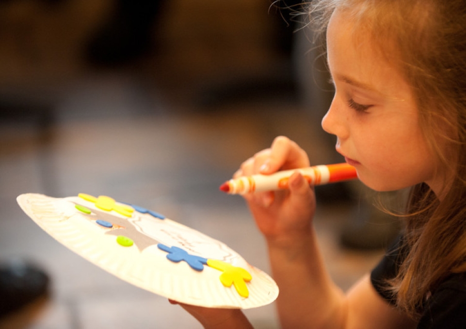 Young girl drawing on a paper plate with a marker