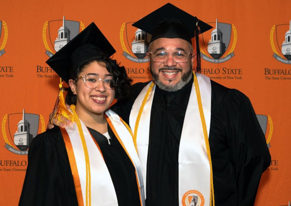 Clarimar and Cesar Galarza standing side by side smiling in caps and gowns