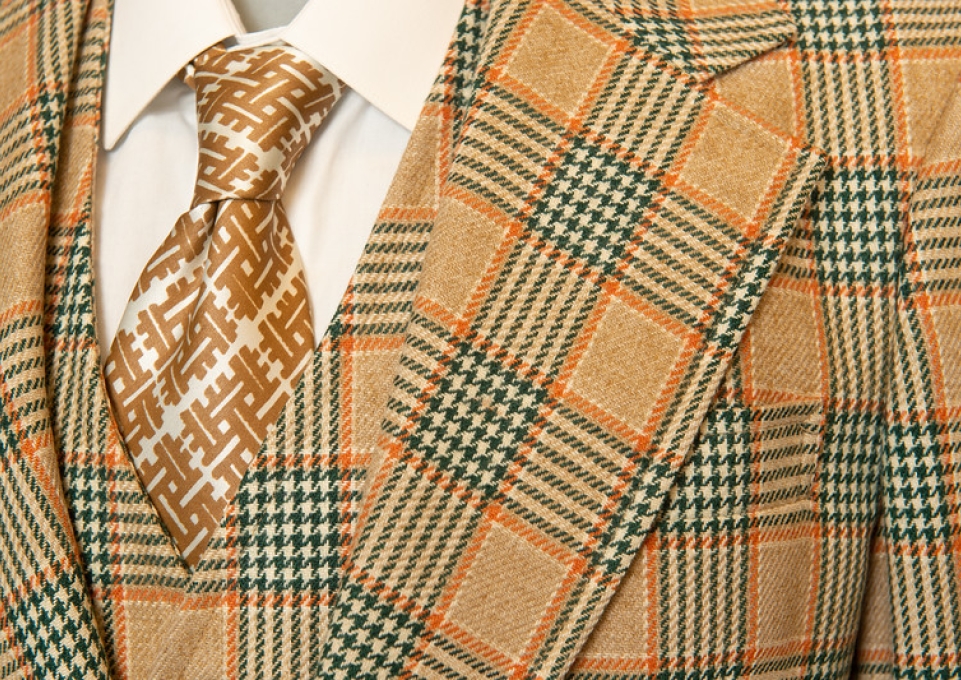 Detail of camel, orange, and black plaid sport coat and matching vest with print tie