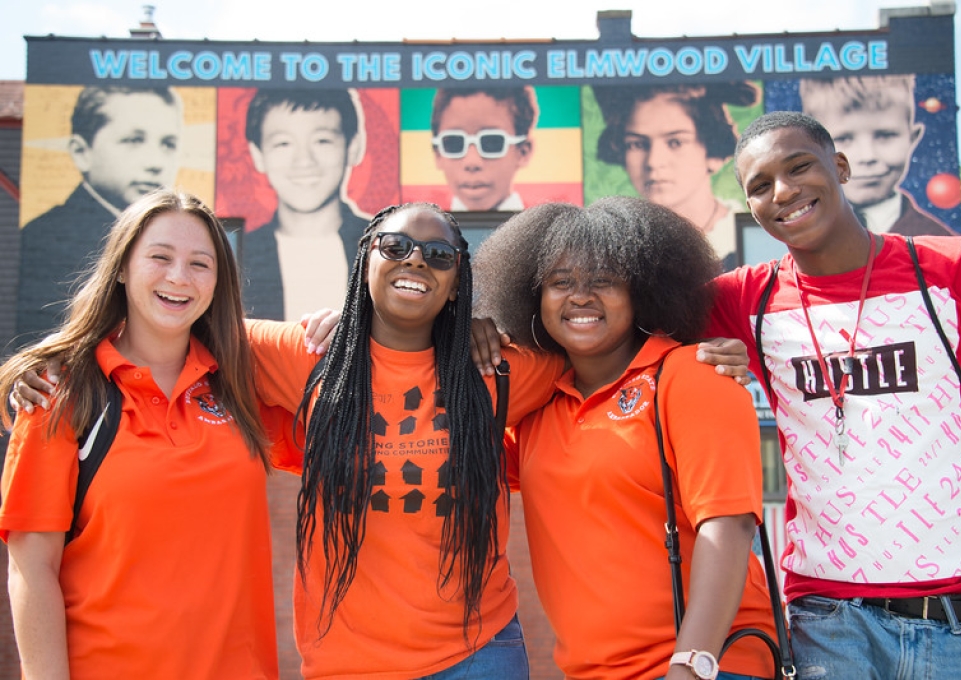 Four Buffalo State students pose in front of Elmwood Village mural