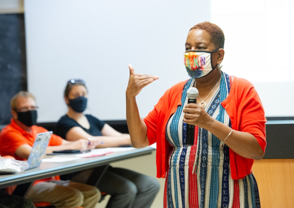 Karen Edmond stands with a microphone in front of the class she is teaching.