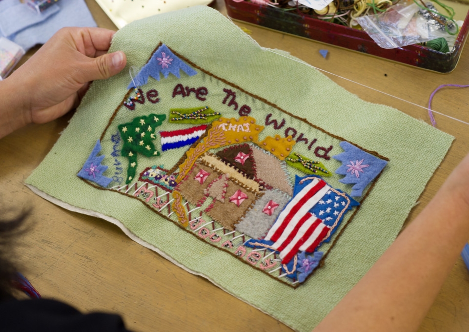 Stitching from Stitch Buffalo's Refugee Women's Workshop that says "We Are The World."