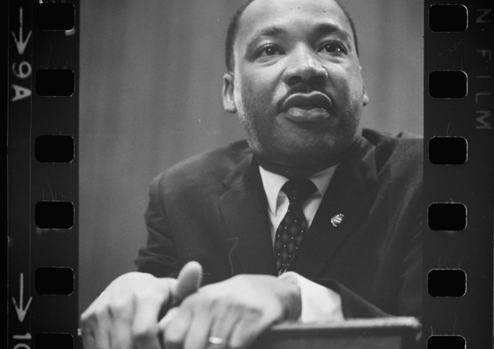Martin Luther King Jr. standing behind and gripping a lectern