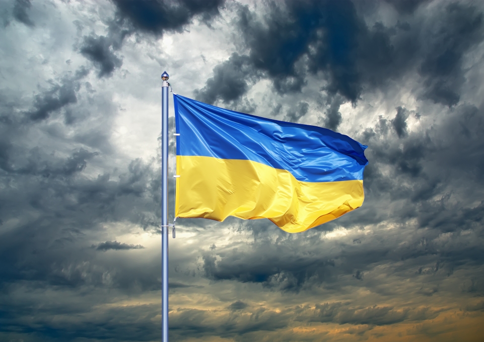 Ukranian flag on a pole against a dark gray cloudy sky