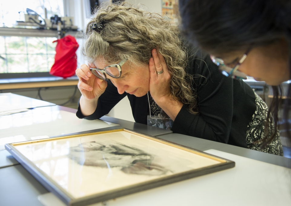 Associate professor Theresa Smith lifting her glasses to examine a sketch