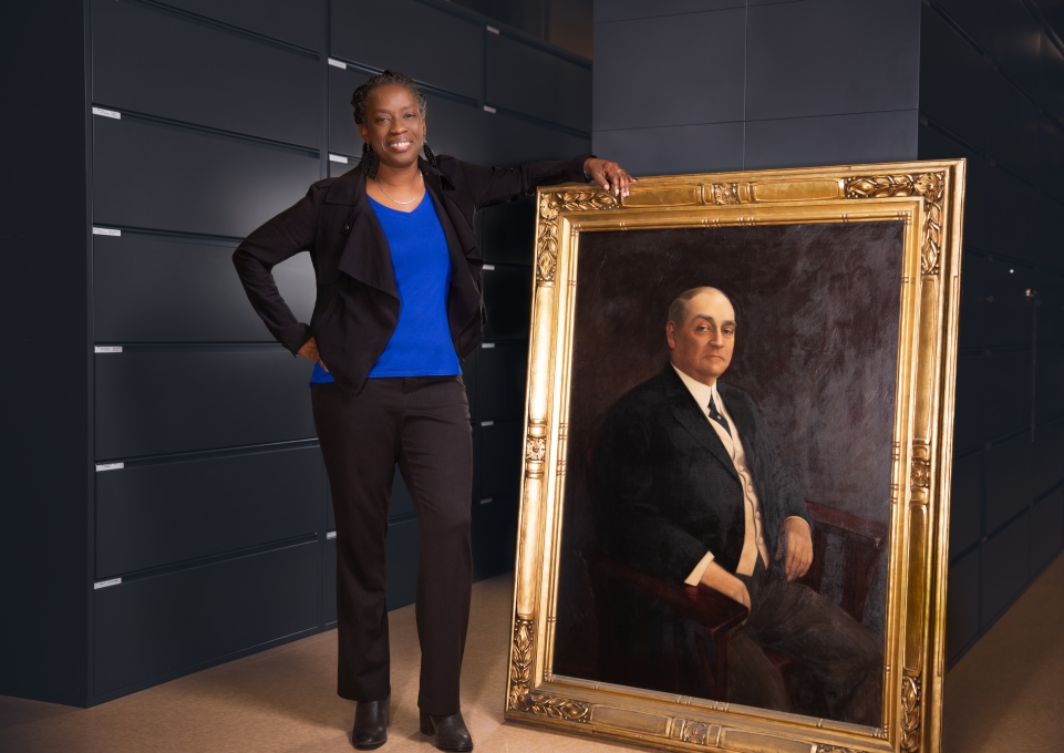 Sheila Rayam stands next to life-size portrait of Edward H. Butler Sr. 