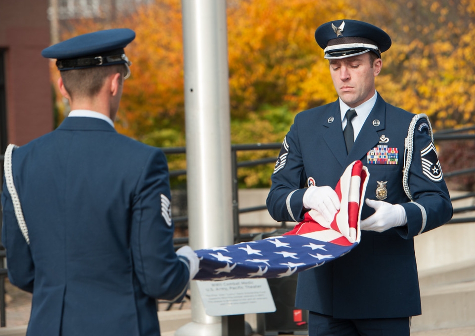 Two service members participating in a flag folding ceremony