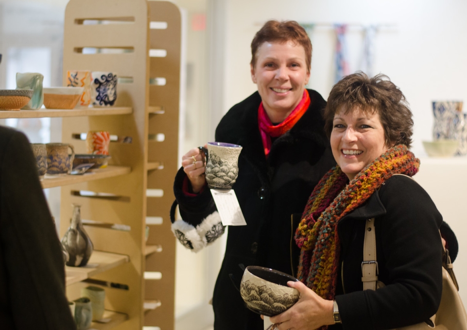 Smiling shoppers holding their wares at the Student Art Sale