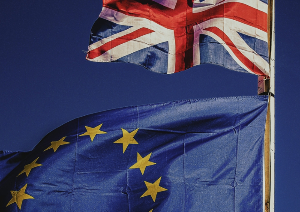 UK flag and EU flag fly together against a blue sky