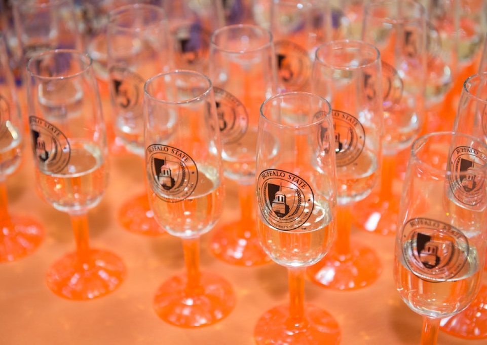 Orange-stemmed champagne glasses with Buffalo State logo