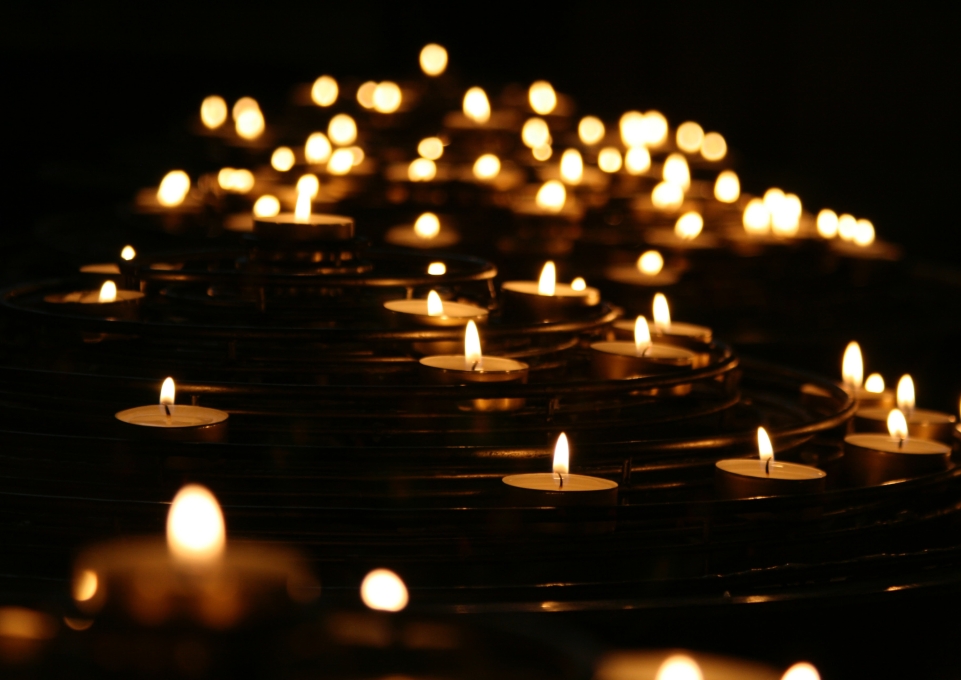 Many tea light candles burning in the darkness