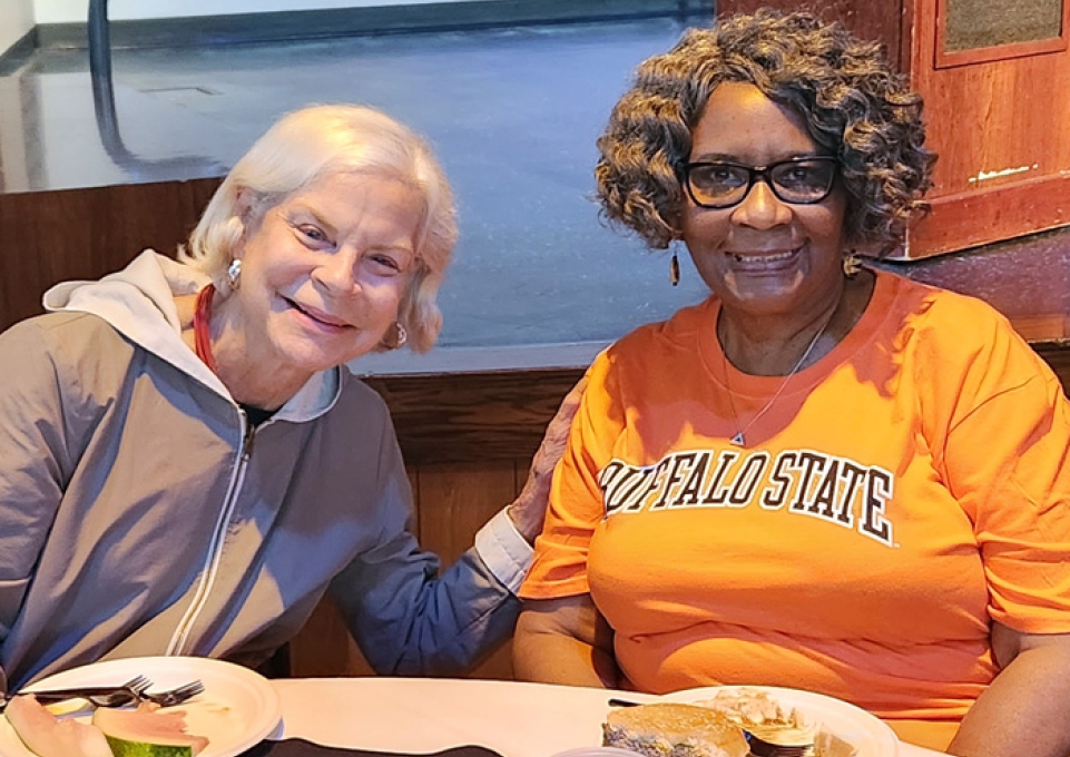 College Council Chair Linda Dobmeier and Interim President Bonnie Durand seated at a table smiling for the camera