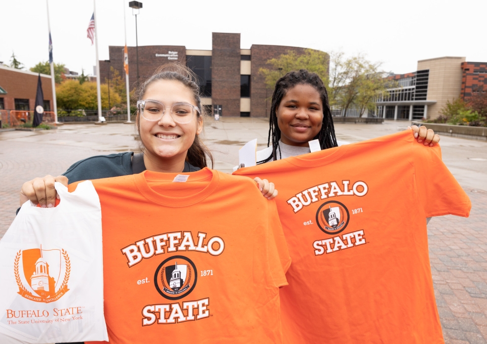 Two prospective students hold Buffalo State t-shirts and smile