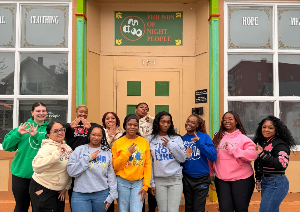 A group of female students outside a building with a sign reading Friends of Night People