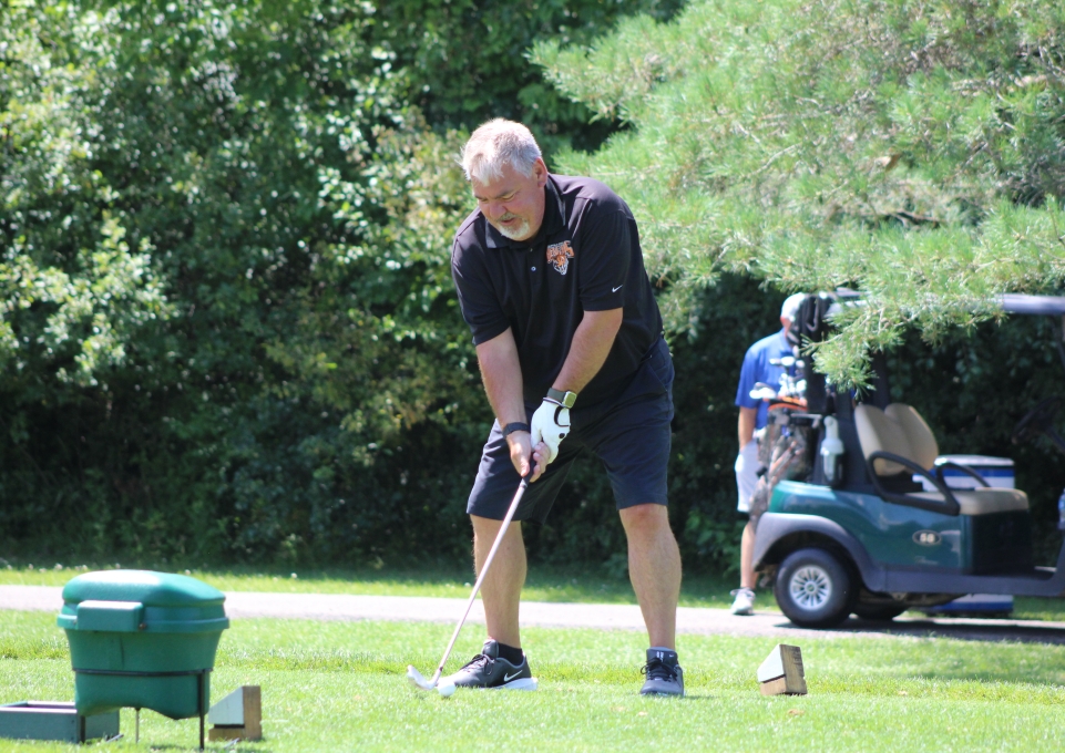 Man wearing a Buffalo State shirt setting up for a golf swing